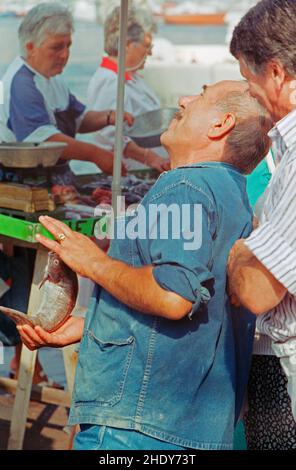 Fischerman präsentiert einen Fisch-, Fischmarkt auf dem Quai des Belges, Alter Hafen, Marseille, 28. August 1991, Département Bouches-du-Rhône, Region Provence-Alpes-Côte d’Azur, Frankreich Stockfoto