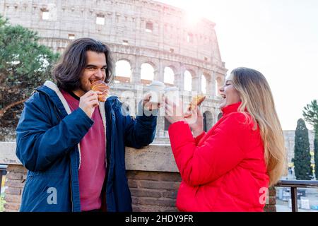 Junges Paar, das nach Rom reist. Das Paar isst ein Croissant und trinkt einen Kaffee vor dem Kolosseum. Stockfoto