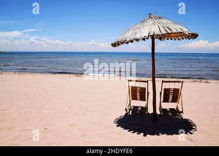 Sonnenschirm und Liegen mit See Titicaca im Hintergrund. Keine Menschen am leeren Strand auf der Insel Taquile in Peru, Südamerika. Stockfoto