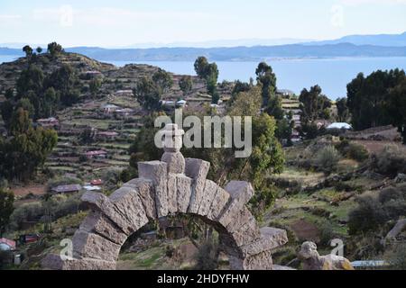 Landschaftsansicht des alten Steinbogens und der archäologischen Ruinen auf der Insel Taquile mit dem Titicacasee in der Ferne. Foto aufgenommen in Peru. Stockfoto