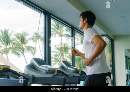 Ein asiatischer Mann trainiert morgens auf einem Laufband in einem Fitnesscenter des Resorts. Stockfoto
