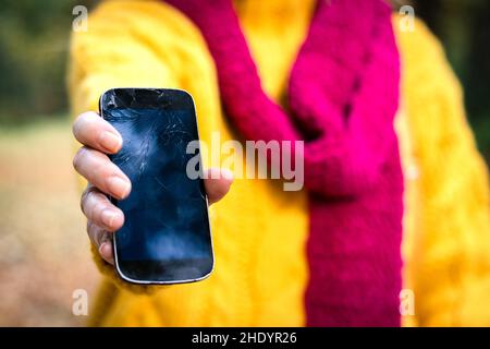 Frau hält ein defektes Smartphone in der Hand. Verärgerte Frau mit beschädigtem Mobiltelefon. Stockfoto