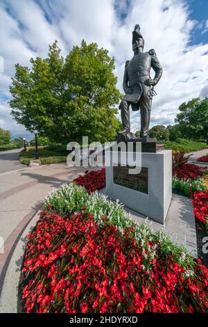 Ottawa, Kanada - 09.04.2019: Vertikale Aufnahme von John durch den Gründer von Bytown, Statue in der kanadischen Hauptstadt. Rote Blumen um. Und blauer Himmel mit weichen Stockfoto