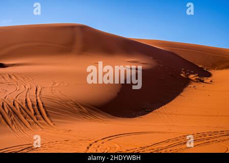 Sanddünen mit Reifenspuren in der Wüste am sonnigen Sommertag gegen den Himmel Stockfoto