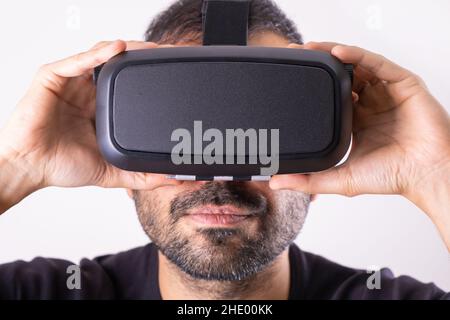 Junger Mann in VR-Brille Headset mit Händen halten, Nahaufnahme Porträt. Virtual Reality, Zukunftstechnologie, Videospiele im Bildungsbereich Stockfoto