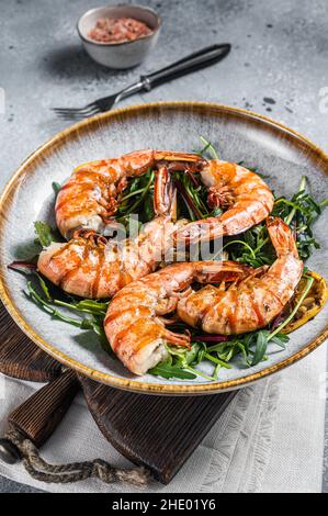Salat mit gegrillten Riesengarnelen auf dem Teller. Grauer Hintergrund. Draufsicht Stockfoto