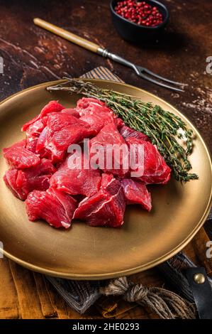 Rohes Lammkotelfleisch in Würfel mit Thymian. Dunkler Hintergrund. Draufsicht Stockfoto