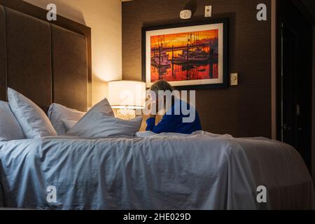 Ältere Frau liest im Bett; Hotelzimmer; Newport; Oregon; USA Stockfoto