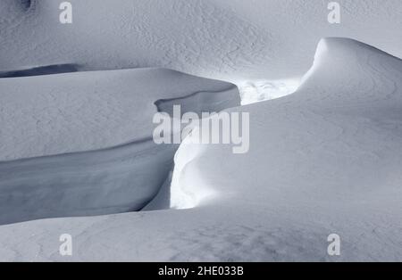 Neu gefallener Schnee in weichen Pflaumen, Textur auf dem Boden. Strahlender Sonnenschein, Berghang. Analog. Stockfoto