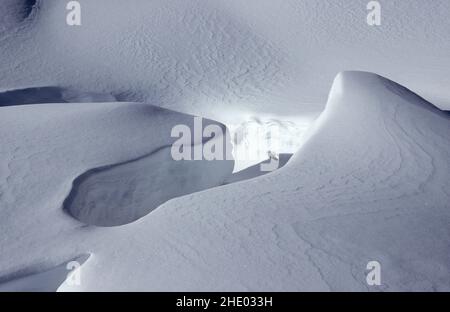 Neu gefallener Schnee in weichen Pflaumen, Textur auf dem Boden. Strahlender Sonnenschein, Berghang. Analog. Stockfoto