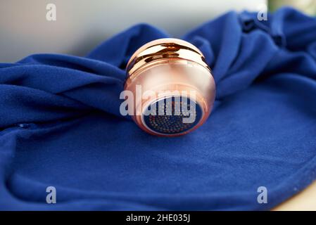 Flusenentferner mit goldener Verzierung liegt auf blauer Strickjacke Stockfoto