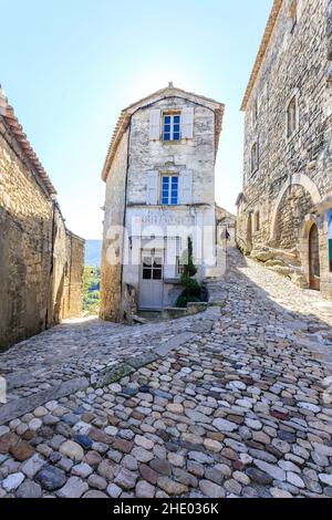 Frankreich, Vaucluse, Parc Naturel Regional du Luberon (Naturpark Luberon), Lacoste, gepflasterte Gasse im Dorf mit einem Radfahrer // Frankreich, VA Stockfoto