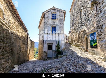 Frankreich, Vaucluse, Parc Naturel Regional du Luberon (Naturpark Luberon), Lacoste, gepflasterte Gasse im Dorf mit einem Radfahrer // Frankreich, VA Stockfoto