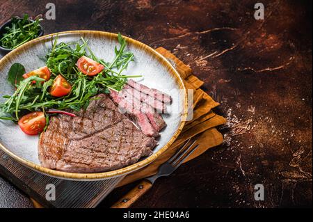 Diner mit gegrilltem Rinderfleisch-Steaks und Gemüsesalat. Dunkler Hintergrund. Draufsicht. Speicherplatz kopieren Stockfoto