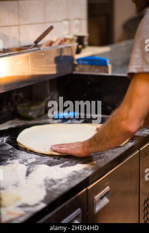 Mann, der einen runden Teig für die Pizza macht Stockfoto