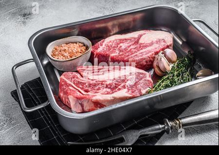 Ungekochte rohe Chuck Eye Roll Steaks in einer Stahlküchenschale. Grauer Hintergrund. Draufsicht Stockfoto