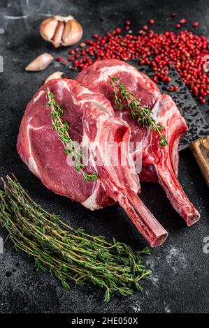 Rohe Tomahawk Rib Kalbssteaks auf Fleischspalter. Schwarzer Hintergrund. Draufsicht Stockfoto