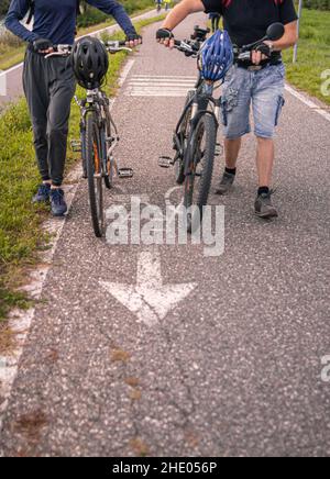 Vater und Sohn schieben E-Bike und Mountainbike nach einer Radtour in Terlan, Südtirol, Italien; gesundes, aktives Lifestyle-Konzept Stockfoto