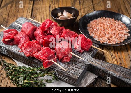 Rohschinkebab, Fleisch mit Gewürzen und Kräutern auf Spieße. Holzhintergrund. Draufsicht Stockfoto