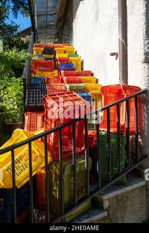 Farbige Kunststoffkisten, gestapelt auf einer Treppe in einem ländlichen Dorf im Apennin Stockfoto