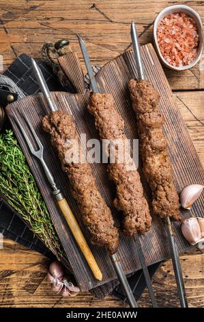 BBQ gegrillter Adana Kebab auf Spieße aus Hackfleisch aus Lammfleisch. Holzhintergrund. Draufsicht Stockfoto