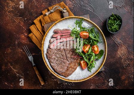 Diner mit gegrilltem Rinderfleisch-Steaks und Gemüsesalat. Dunkler Hintergrund. Draufsicht Stockfoto