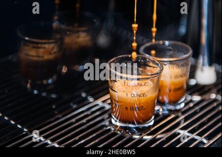 Nahaufnahme des Kaffees, der in Tassen auf einer Kaffeemaschine gegossen wurde Stockfoto