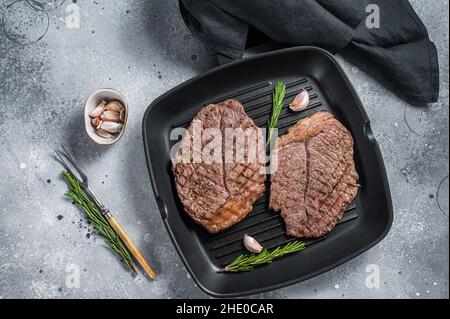 Geröstet auf Grillpfanne Rindfleisch marmorierte Fleischsteaks. Grauer Hintergrund. Draufsicht Stockfoto