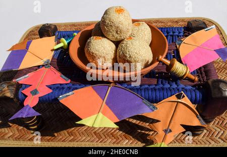 Til ladoo oder Til baati laddu, indische süße Knödel süße Kugeln aus weißen Sesamsamen serviert in irdenen Teller auf Mini-Kinderbett mit Outdoor-Backgroun Stockfoto