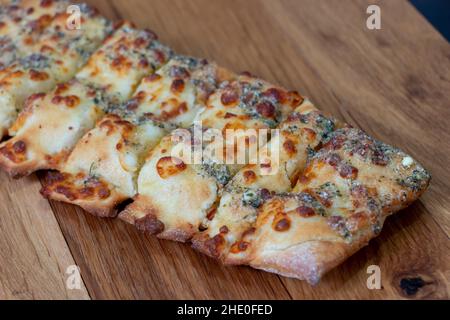 Gerösteter Käse und Knoblauchbrot. Italienische Küche. In Scheiben geschnittenes Knoblauchbrot mit weißer Sauce auf einem Holzhintergrund. Stockfoto