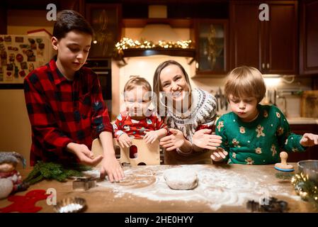 Familie mit drei Kindern kocht Ingwerkekse. Frohe Weihnachten, Frohes neues Jahr. Familienzeit, Vorbereitung auf den Urlaub. Stockfoto