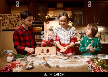 Familie mit drei Kindern kocht Ingwerkekse. Frohe Weihnachten, Frohes neues Jahr. Familienzeit, Vorbereitung auf den Urlaub. Stockfoto