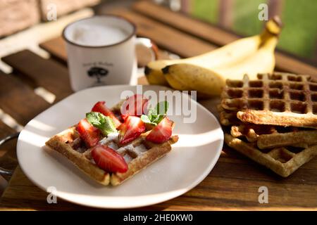 Waffeln mit Erdbeeren, Bananen und Honig. Stockfoto