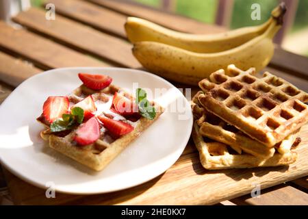 Waffeln mit Erdbeeren, Bananen und Honig. Stockfoto