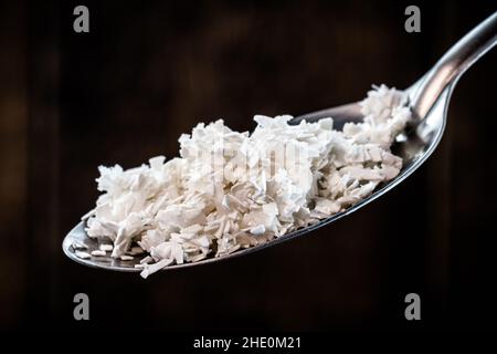 Löffel mit gemahlener und zerdrückter Eierschale, isoliert auf schwarzem Hintergrund, selbstgemahlener Dünger für Pflanzen. Stockfoto