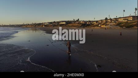 Luftaufnahme eines jungen Mannes (Modell veröffentlicht), der auf dem elektrischen OneWheel-Skateboard am Pacific Beach bei Sonnenuntergang, San Diego, Kalifornien, USA, reitet Stockfoto