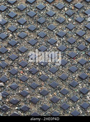 Metall Straßenabdeckung Hintergrund. Dunkle Metalloberfläche mit Rautenornament und Sand Stockfoto