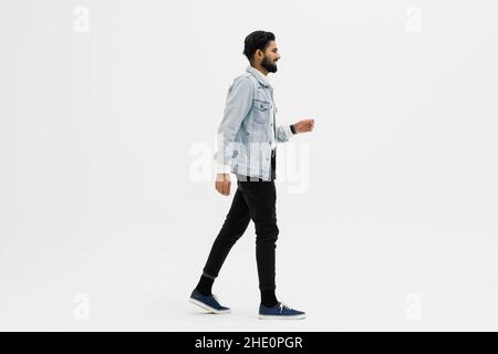 In voller Länge Seitenaufnahme eines gutaussehenden Bartmenschen, der auf weißem Hintergrund läuft Stockfoto