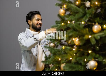 Aufgeregt erstaunt Mann in weihnachtsmann Hut Dekoration Neujahr Baum immergrün zu Hause Stockfoto