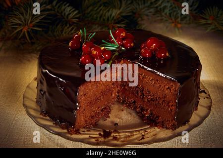 Der Mozartkuchen besteht aus 3 Schichten Schokoladenkuchen, der mit Cognac mit frischen Beeren und Rosmarin und Zweigen eines Weihnachtsbaums imprägniert ist Stockfoto