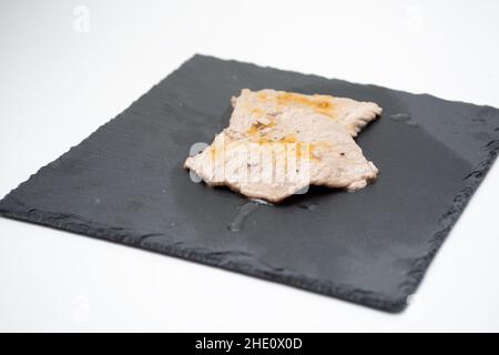 Kalbsfleisch gewürzt mit Aromen im Vordergrund auf einem gusseisernen Schneidebrett Stockfoto