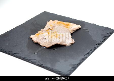 Kalbsfleisch gewürzt mit Aromen im Vordergrund auf einem gusseisernen Schneidebrett Stockfoto
