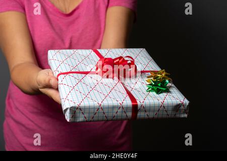 Frau reicht ein eingewickeltes Geschenk-selektiver Fokus Stockfoto