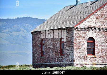 Altes rot-weißes Ziegelgebäude mit gewölbtem Windows Mountain- und Sky-Hintergrund Stockfoto