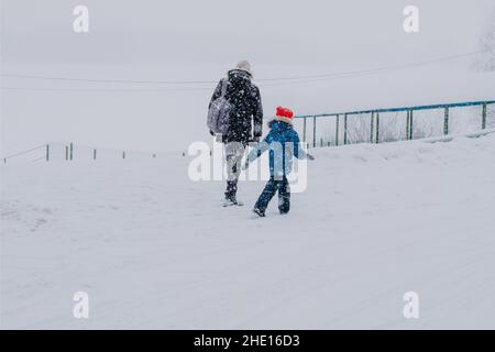 Vater und Sohn während eines Schneesturms auf dem Feld. Reisende blieben auf der Straße stecken Stockfoto