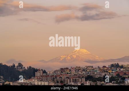 Quito Stadtbild bei Sonnenuntergang mit schneebedeckter Vulkan Cayambe, Anden, Ecuador. Stockfoto