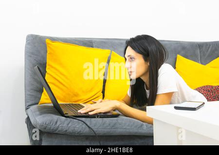 Nahaufnahme einer kaukasischen Frau, die im Bett lag und mit dem sie zum Notizbuch tippte Stockfoto