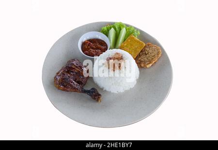 Pecel Ayam oder Ayam Penyet ist ein traditionelles indonesisches gebratenes Huhn mit frischem Gemüse, Chilisauce oder Sambal, Tofu und Tempeh Stockfoto