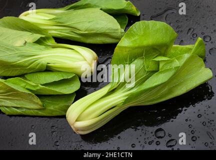 Frisch gewaschene rohe Bok Choy auf schwarzem Tisch mit Wassertropfen Stockfoto