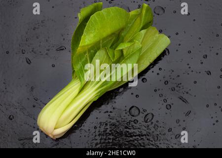 Frisch gewaschene rohe Bok Choy auf schwarzem Tisch mit Wassertropfen Stockfoto